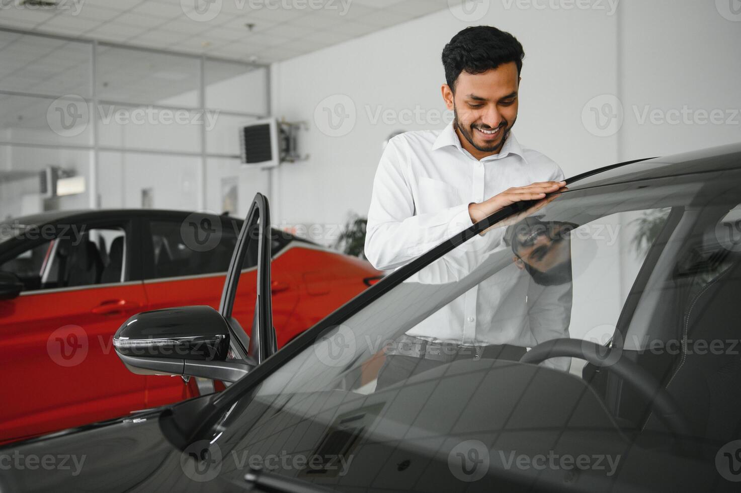 A young Indian man chooses a new car at a car dealership photo