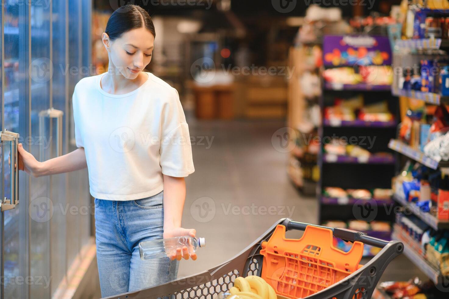 Happy young woman looking at product at grocery store. Smiling woman shopping in supermarket photo