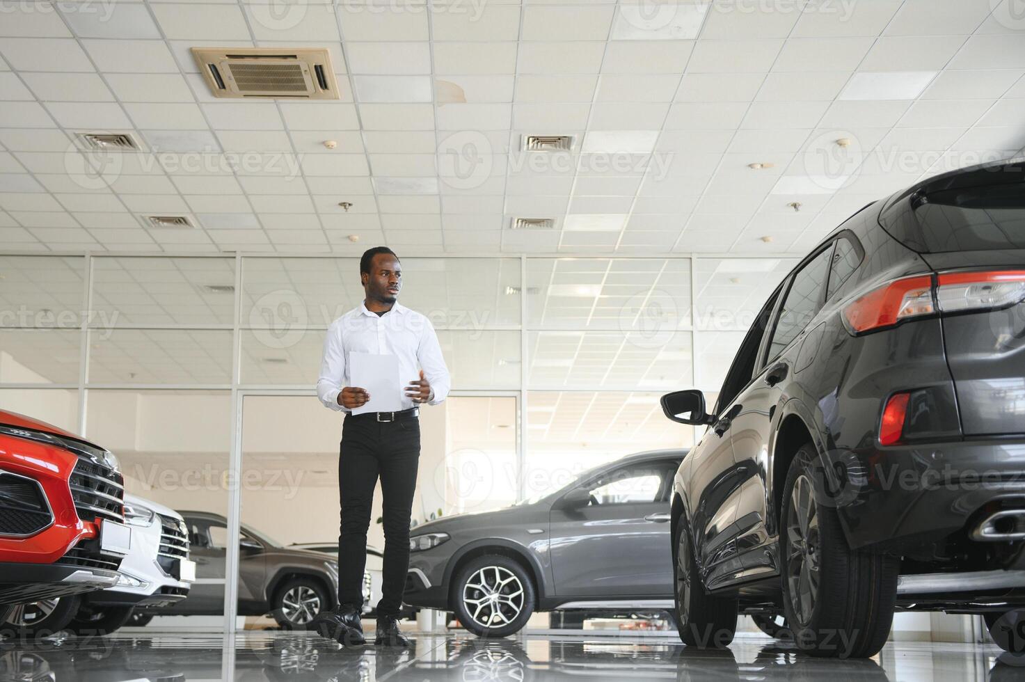 retrato de hermoso africano americano vendedor a lugar de trabajo en coche sala de exposición foto