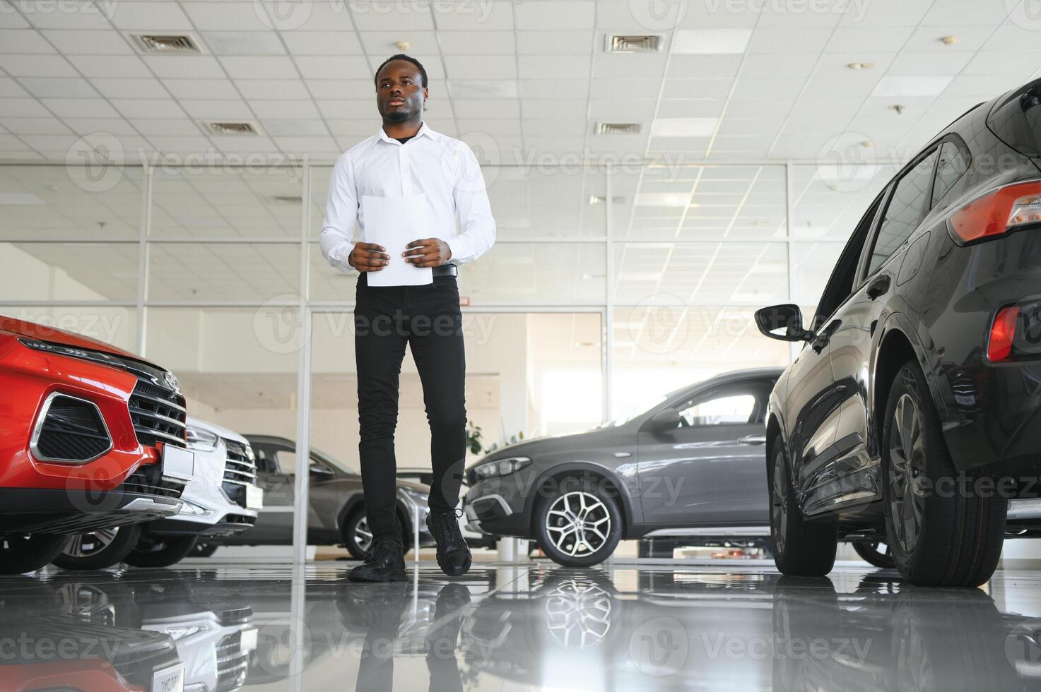 retrato de hermoso africano americano vendedor a lugar de trabajo en coche sala de exposición foto