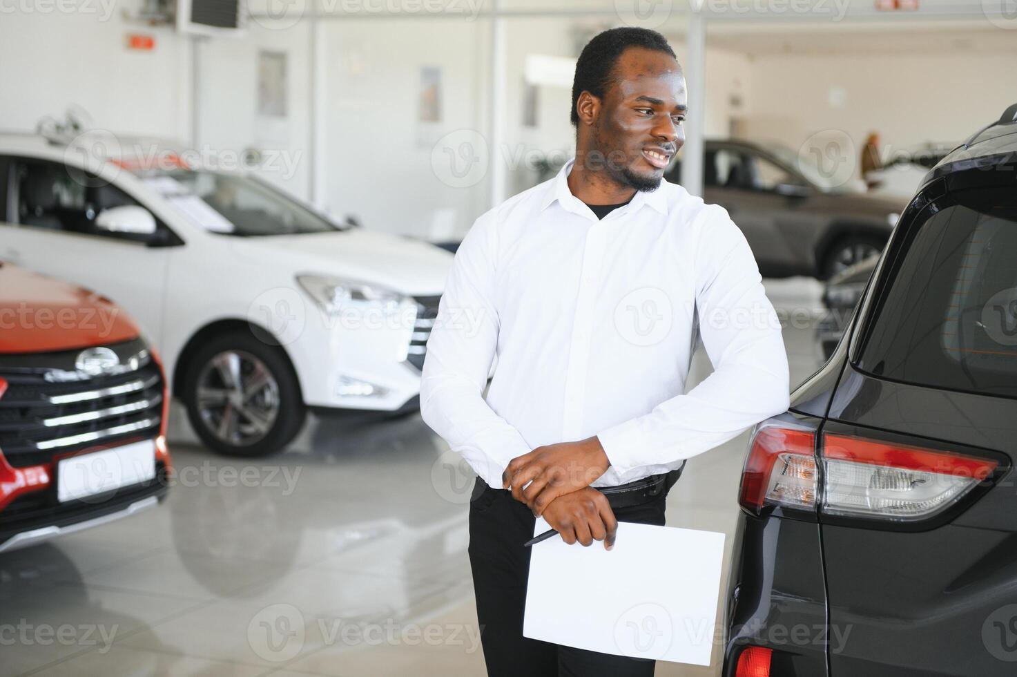 carros concesión concepto. auto vendedor afro hombre en pie en automóvil centrar foto