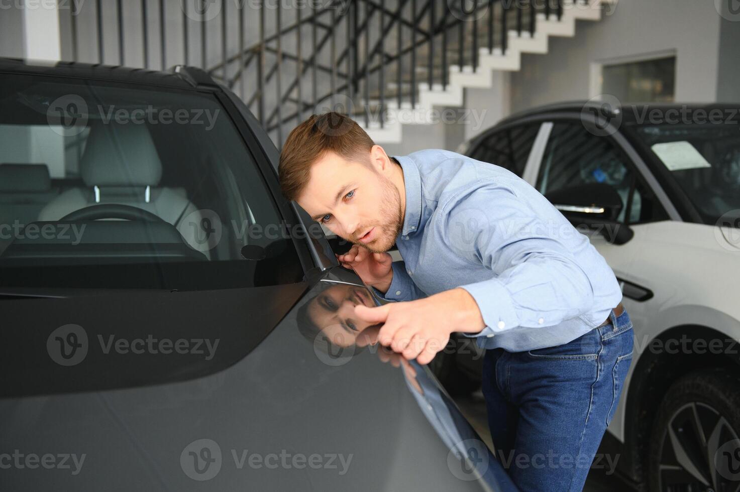 Young man, selling electric cars in the showroom. Concept of buying eco-friendly car for family photo