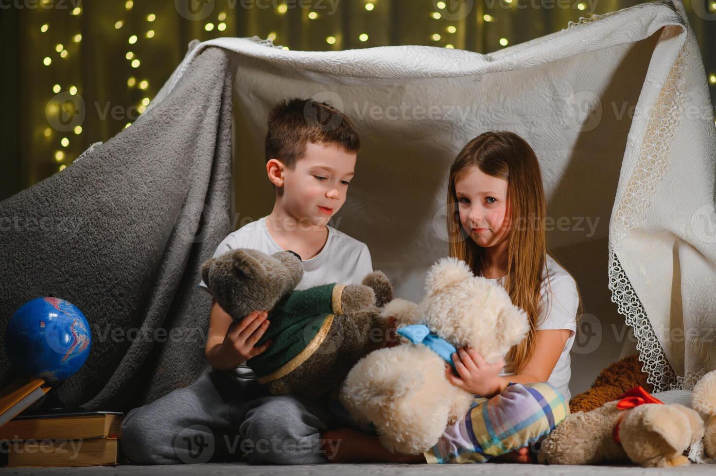 children boy and girl playing and frighten each other with flashlight in tent at night. photo
