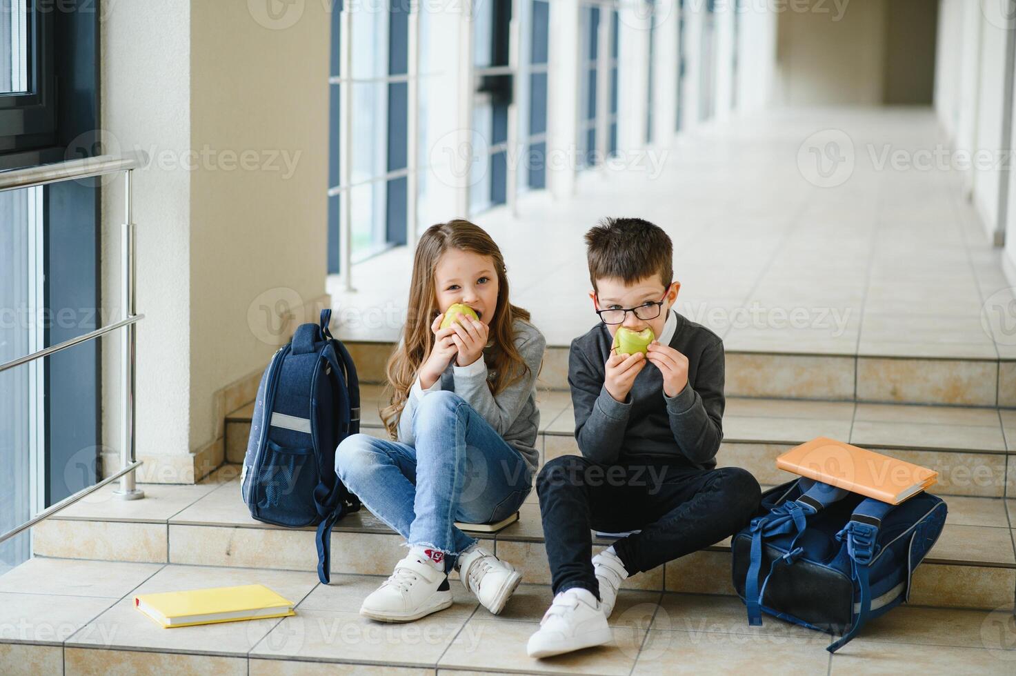 Group of classmates having lunch during break with focus on smiling girl with apple. photo