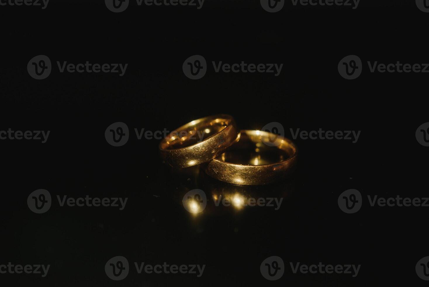 Elegant wedding rings for the bride and groom on a black background with highlights, macro, selective focus. photo