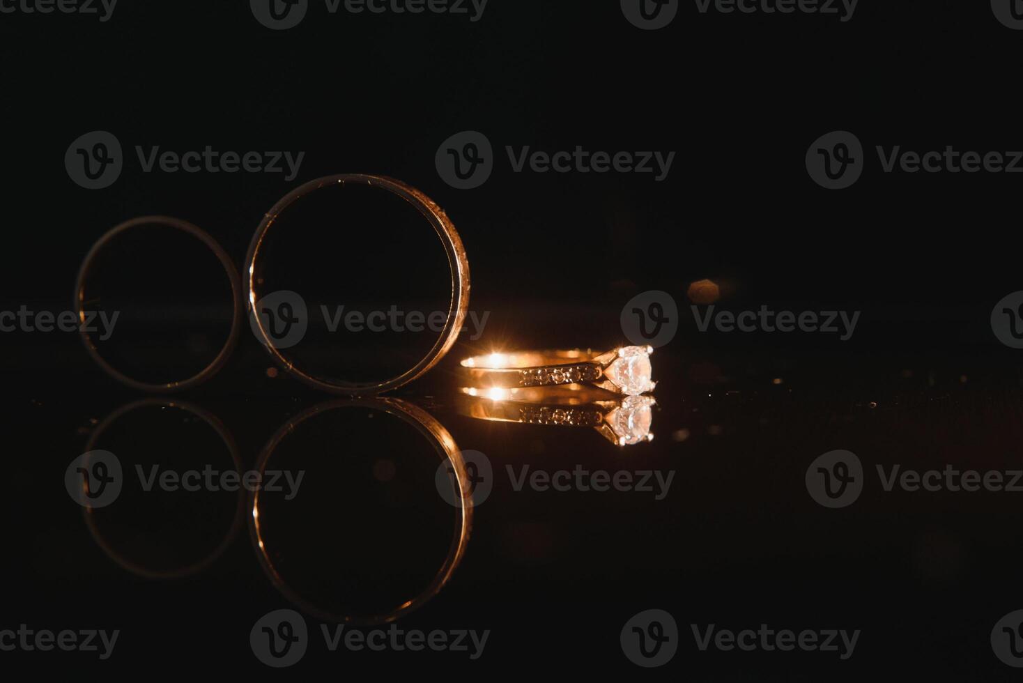 Elegant wedding rings for the bride and groom on a black background with highlights, macro, selective focus. photo