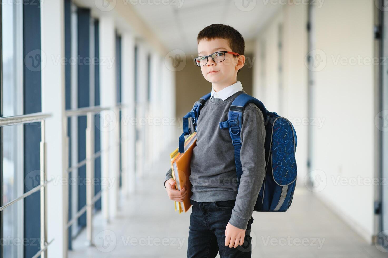 Schoolboy with schoolbag and books in the school. Education concept. Back to school. Schoolkid going to class. Stylish boy with backpack. Boy ready to study. photo