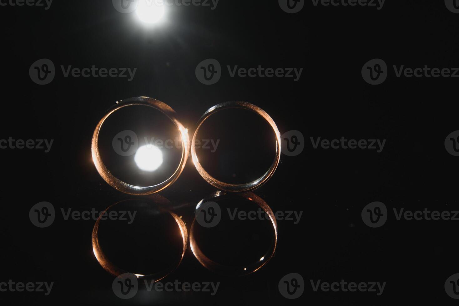 Elegant wedding rings for the bride and groom on a black background with highlights, macro, selective focus. photo