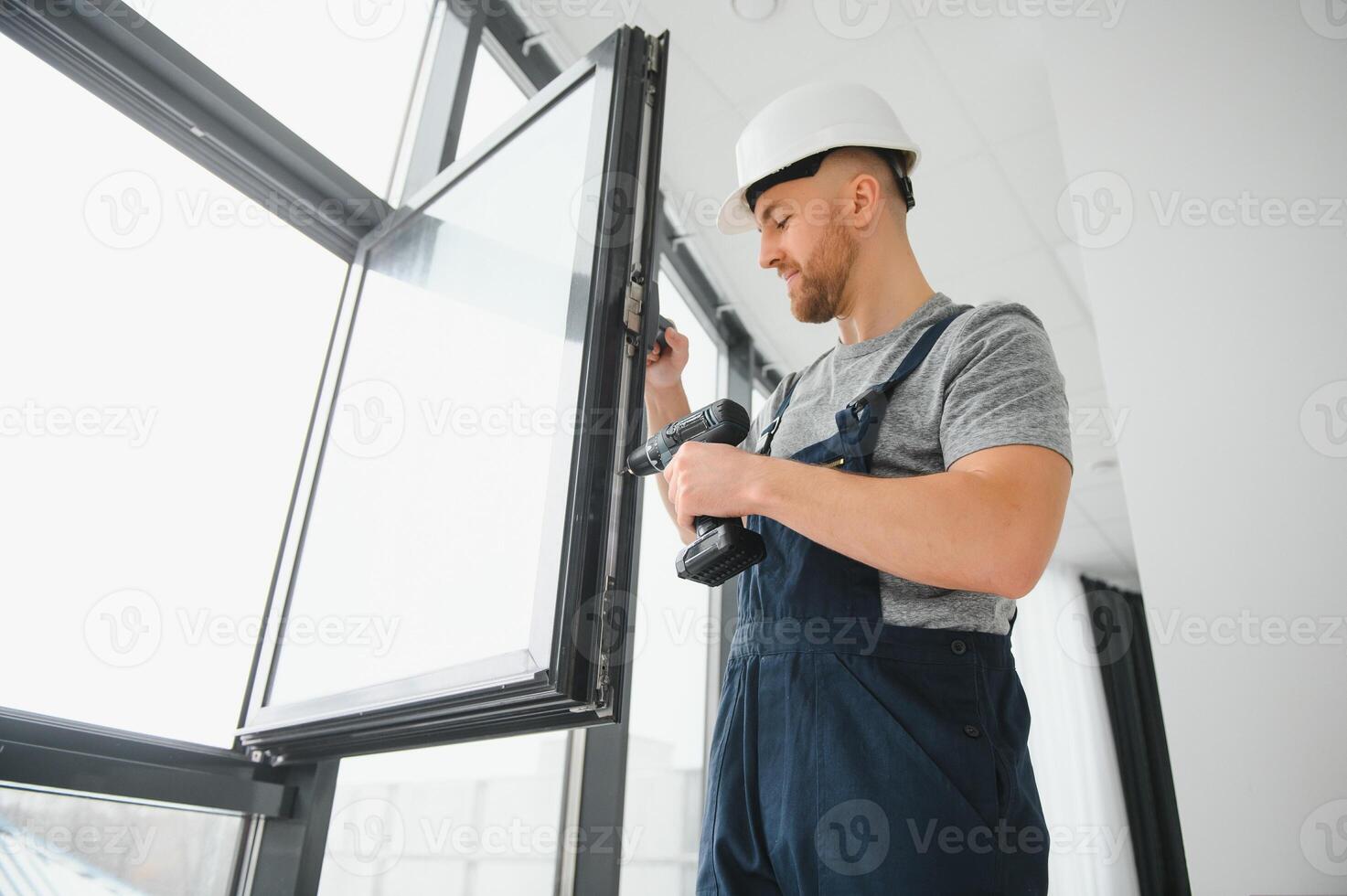 Construction worker repairing plastic window with screwdriver indoors, space for text. Banner design photo