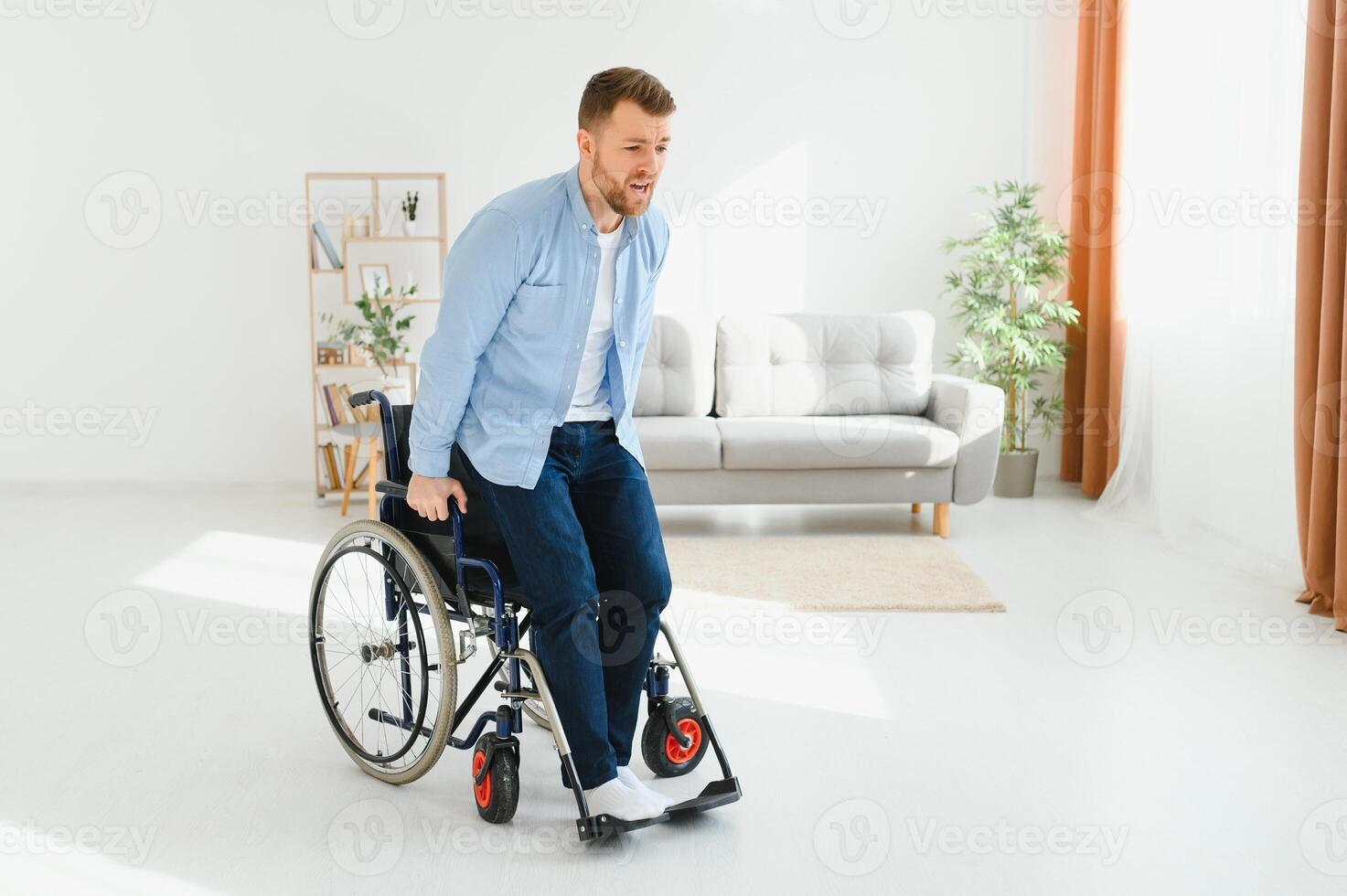 young man trying to get up from wheelchair at home, full length. Impaired black man attempting to stand, exercising his legs indoors, copy space photo