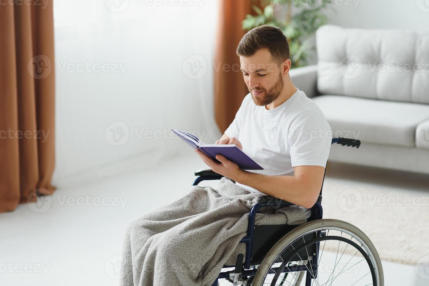 man in wheelchair reading a book at home photo