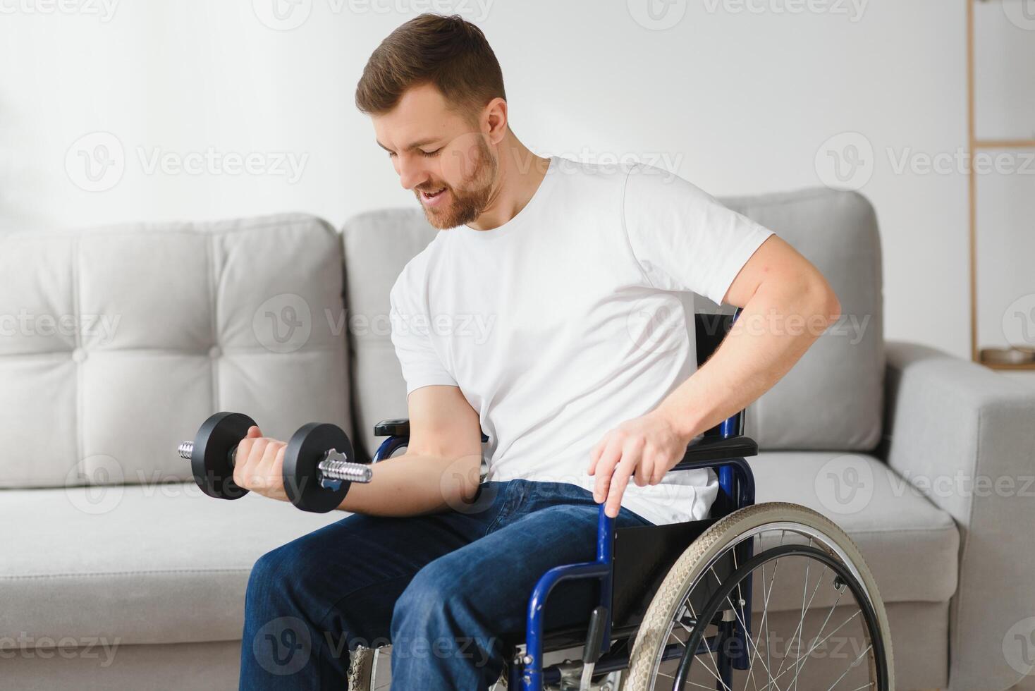 sportsman sitting in wheelchair and outstretching arms with dumbbells during rehabilitation exercise in modern medical center. photo