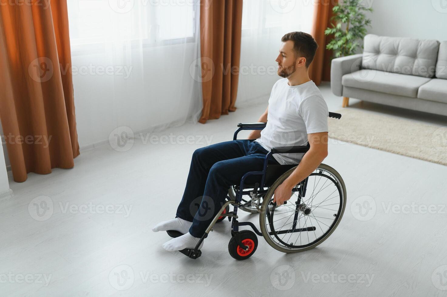 thoughtful young disabled man on wheelchair at home photo