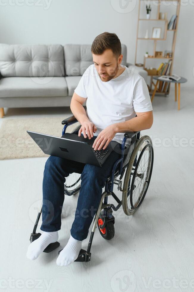 Modern young disabled man in wheelchair having video call photo