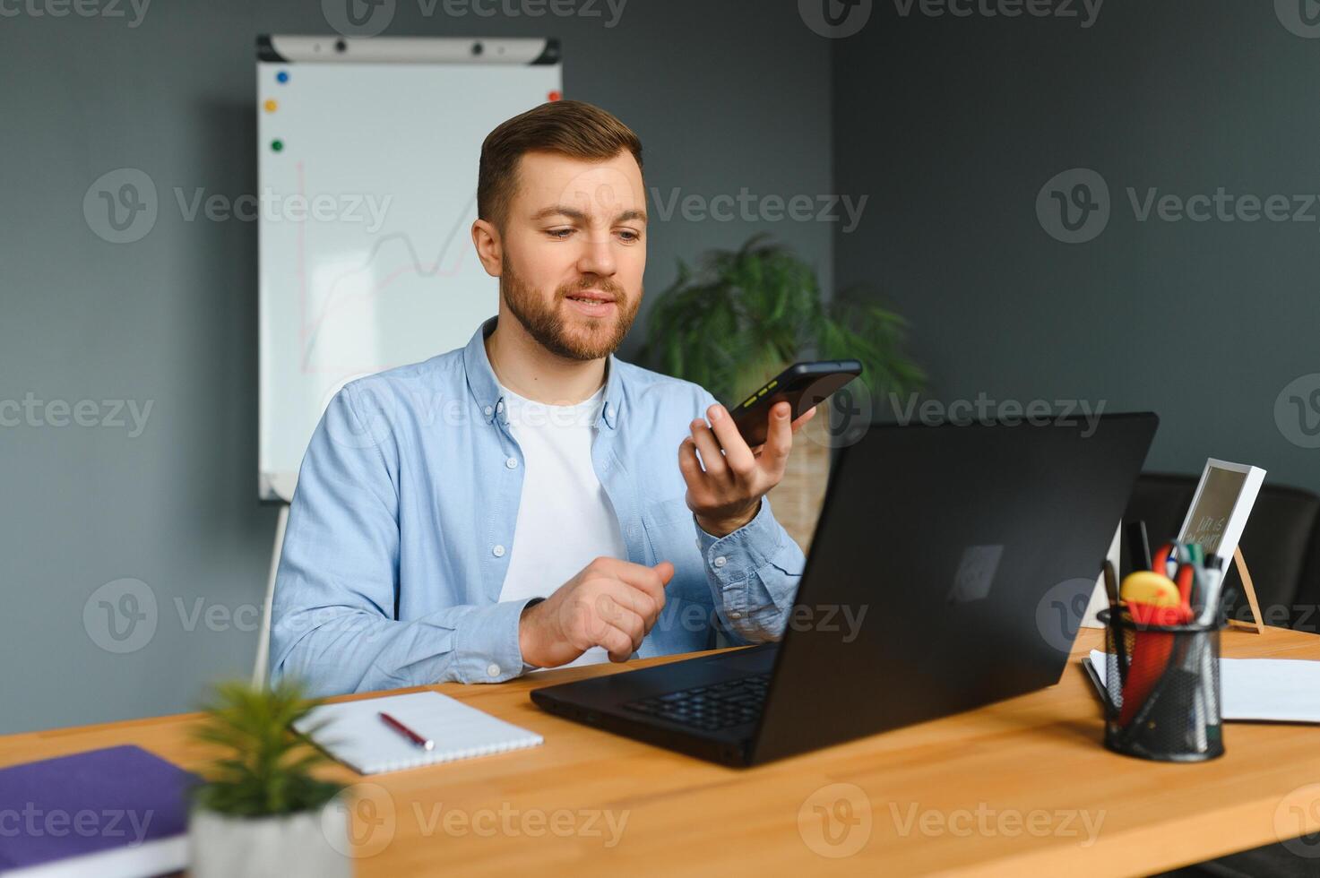 Young happy entrepreneur in wheelchair reading message on smart phone while working at home. photo