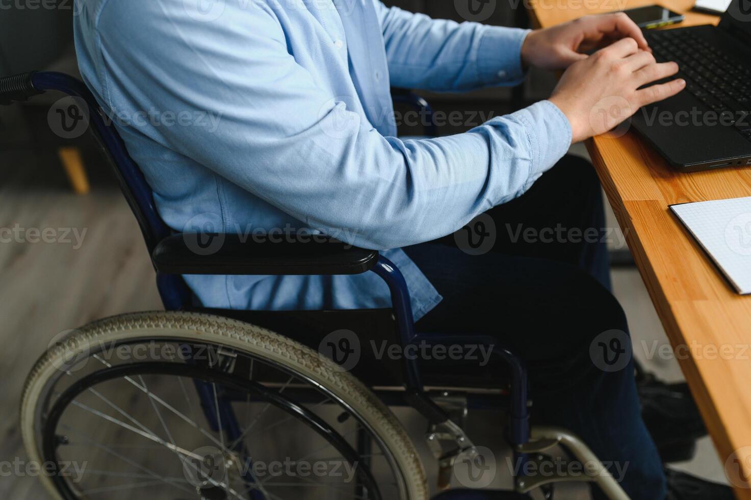 joven contento empresario en silla de ruedas trabajando en ordenador portátil a hogar foto