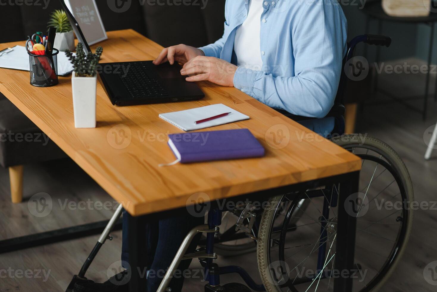 minusválido empresario sentado en silla de ruedas y utilizando computadora en oficina. foto