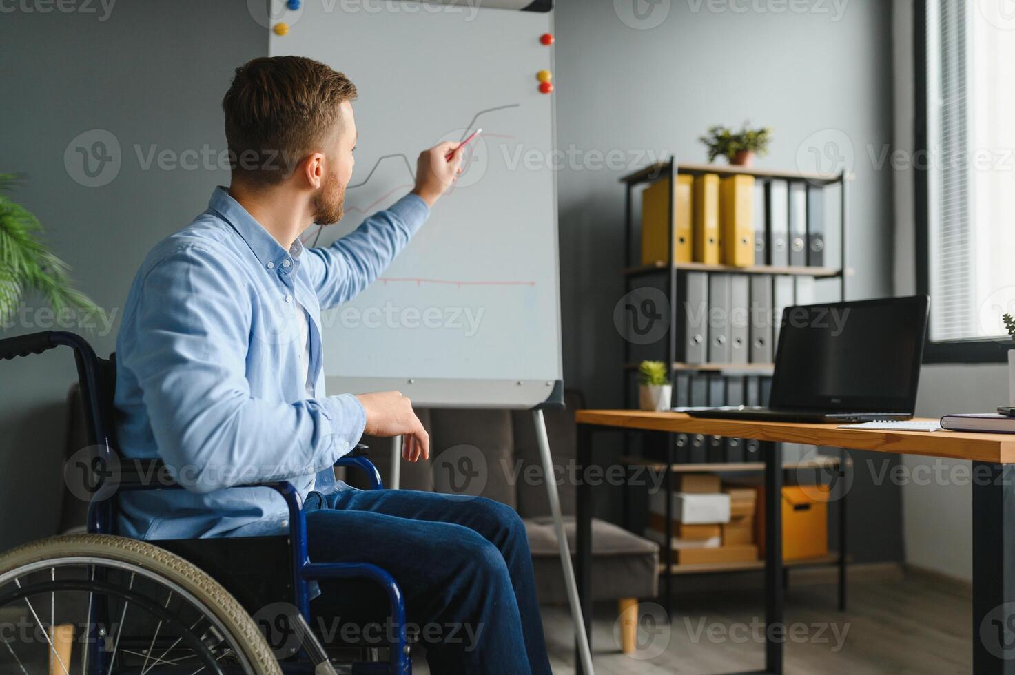 minusválido empresario sentado en silla de ruedas y utilizando computadora en oficina foto