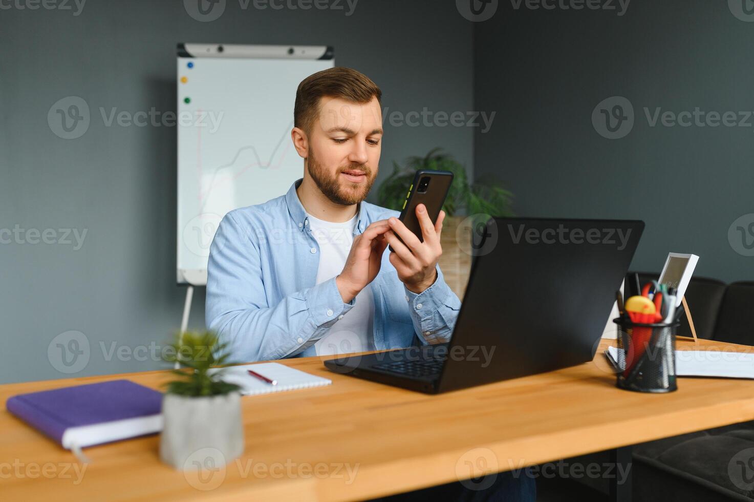 Young happy entrepreneur in wheelchair reading message on smart phone while working at home. photo