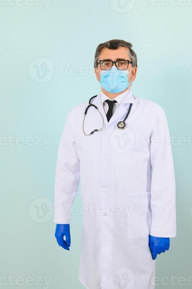 Portrait of a male doctor in a mask and gloves on a blue background. Healthcare concept.. photo