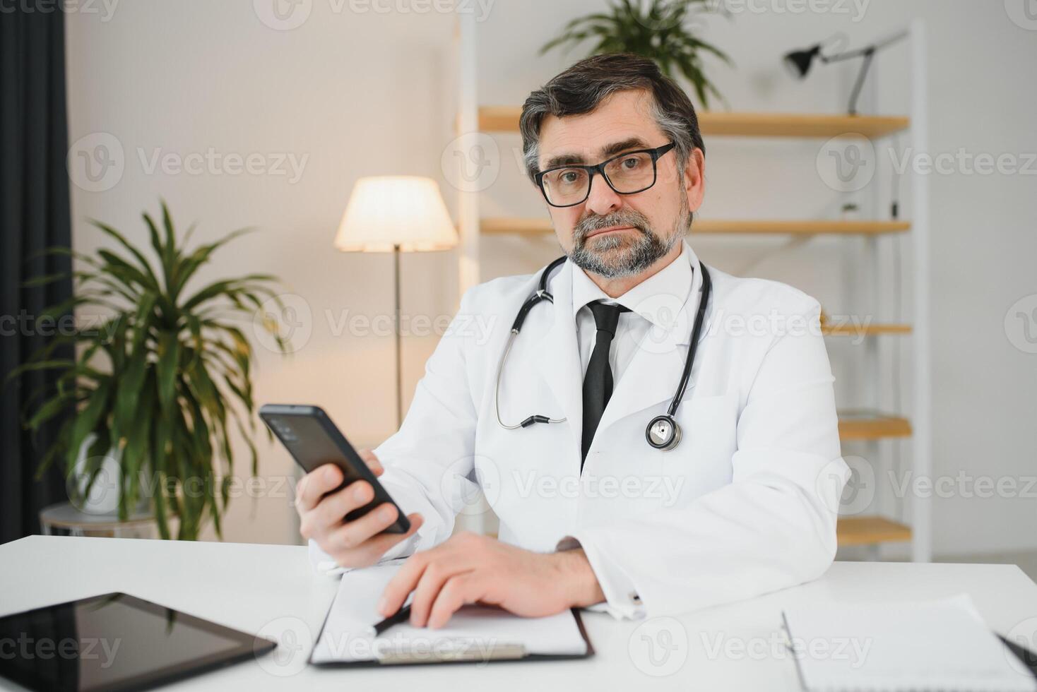 Portrait of senior doctor sitting in medical office. photo