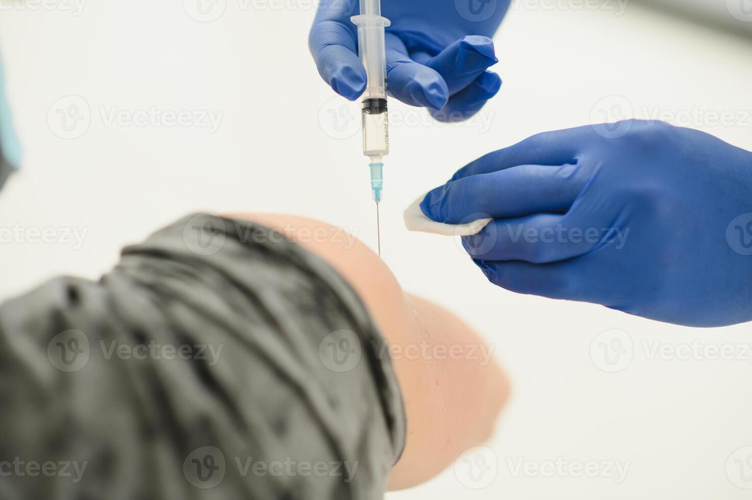 medicine, vaccination and healthcare concept - doctor wearing face protective medical mask for protection from virus disease with syringe doing injection of vaccine to male patient. photo