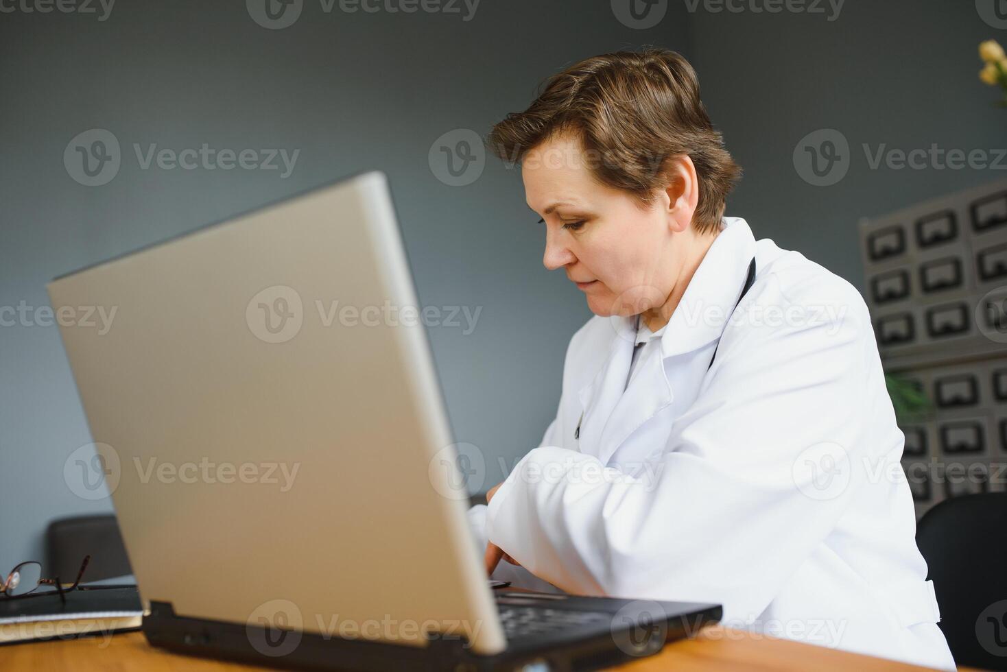 pretty female middle aged medical worker with x-ray standing by window photo
