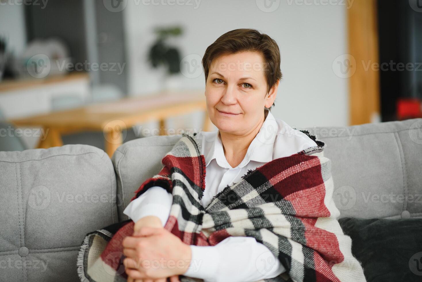 portrait of senior woman at home on sofa with plaid photo