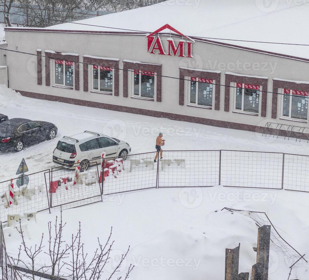 Minsk, Belarus - 01.15.2024 - Shot of the man walking outdoors only in shoes and shorts during winter time. Fitness photo