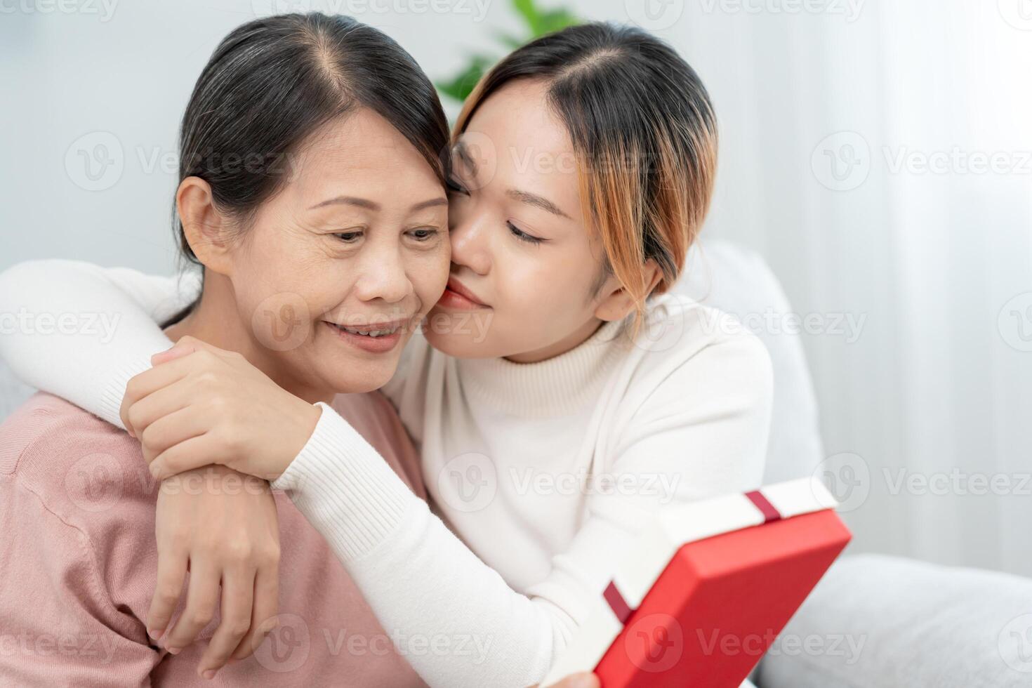 madre día, linda asiático adolescente niña abrazando y besos en el mejilla, maduro medio años mamá. amar, beso, cuidado, contento sonrisa disfrutar familia tiempo. celebrar especial ocasión, contento cumpleaños, alegre Navidad. foto