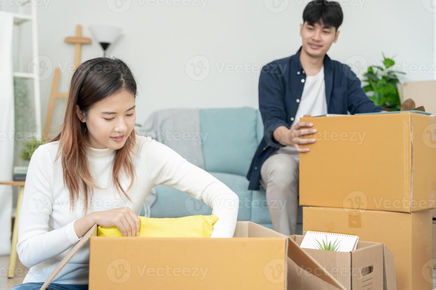 Moviente casa, reubicación Pareja ayuda conjunto y moverse mueble para nuevo departamento, dentro el habitación estaba un cartulina caja Contiene personal pertenencias. moverse en el nuevo Departamento o condominio foto