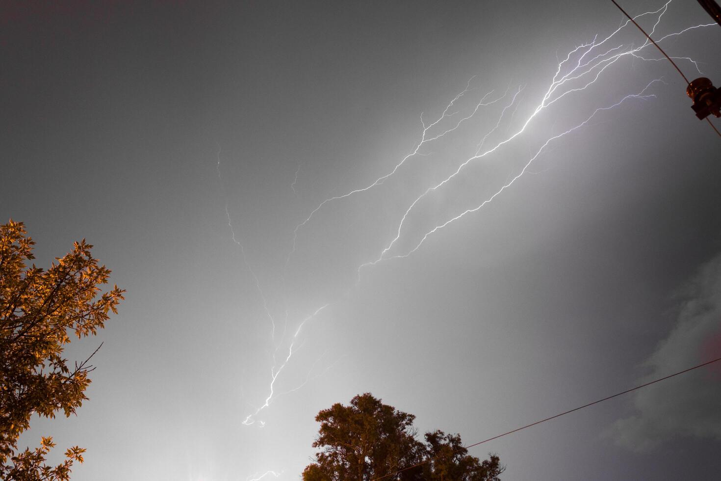 Stormy night with powerful lightnings crossing the sky and thunders roaring through the grey clouds photo