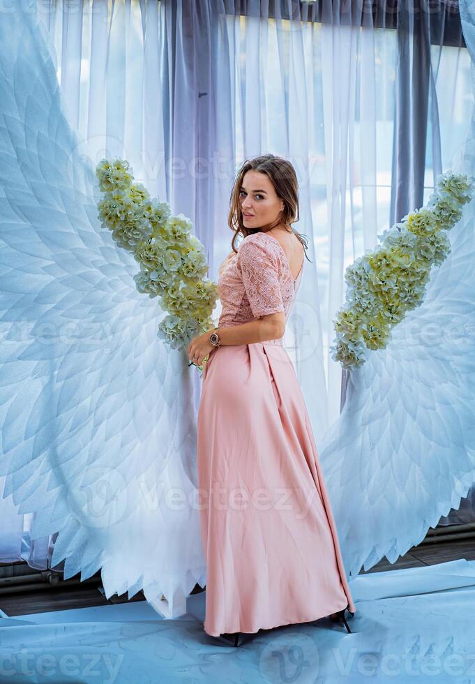 un mujer en pie en frente de un ángel alas fondo foto