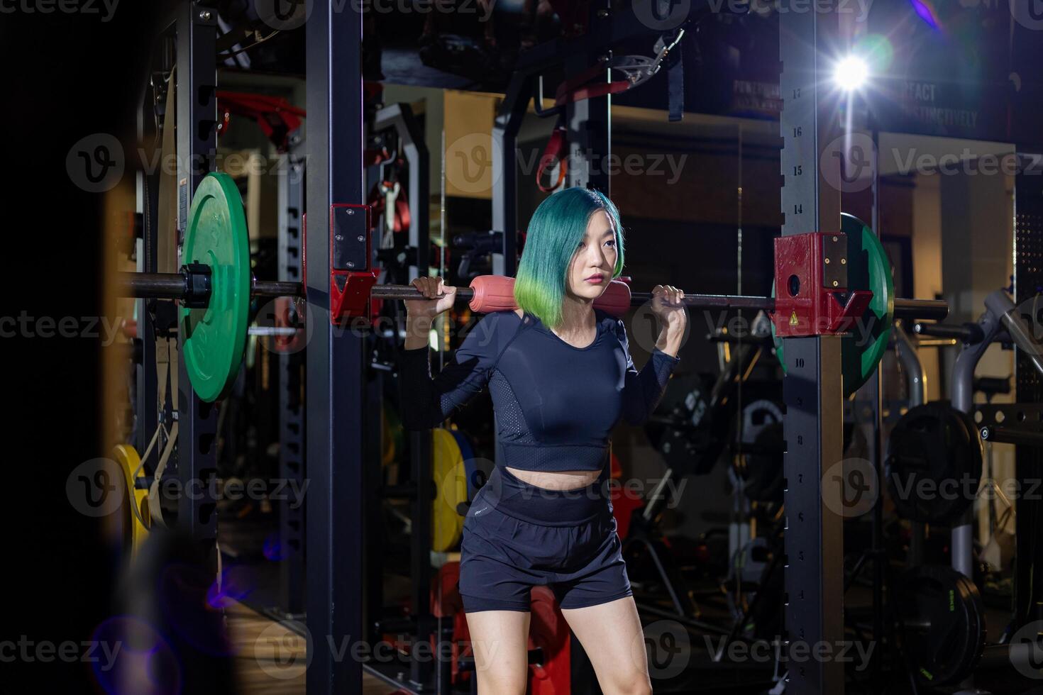 Asian muscular sport woman is practice weight training on deadlift barbell for core muscle inside gym with dark background for exercising and workout concept photo