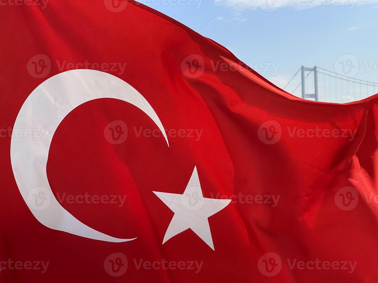Turkish flag fluttering in the wind with Istanbul and the Golden Horn Bridge in the background, Turkey photo