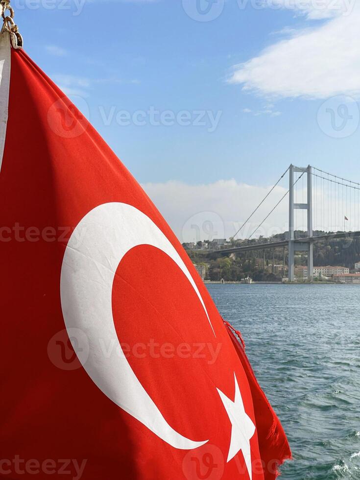 Turkish flag fluttering in the wind with Istanbul and the Golden Horn Bridge in the background, Turkey photo