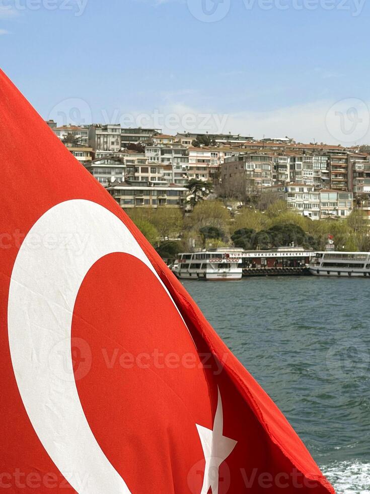 Turkish flag fluttering in the wind with Istanbul and the Golden Horn Bridge in the background, Turkey photo