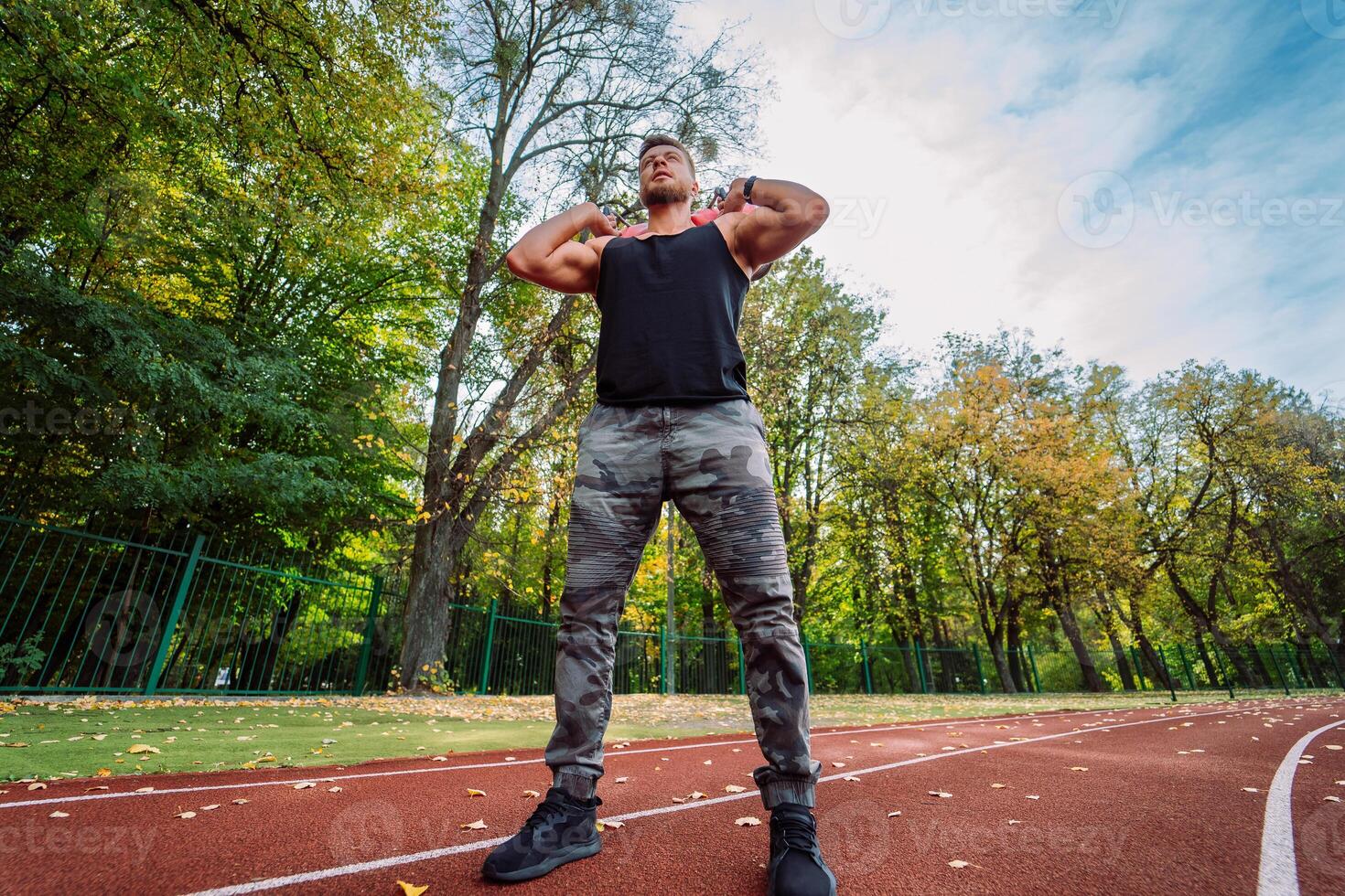 Man Standing on Track with Arms Behind Head. A man standing on a track with his arms behind his head photo