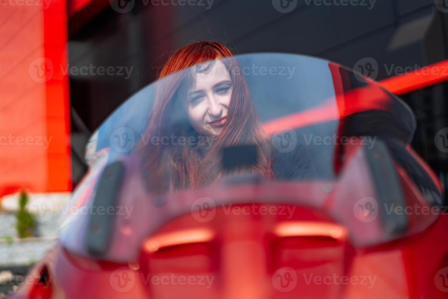 A Woman Looking Out the Window of a Red Car. A woman looking out the window of a red car photo