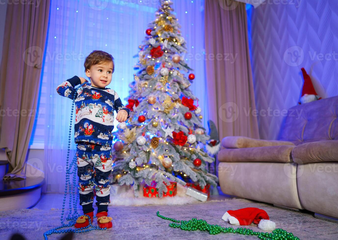A Joyful Little Boy in Front of a Festive Christmas Tree. A little boy standing in front of a christmas tree photo