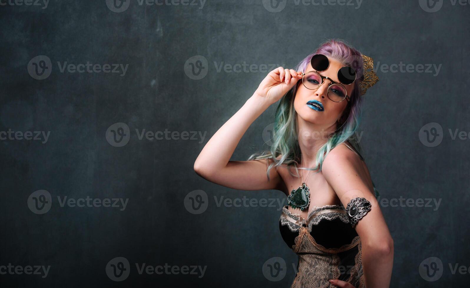 Woman with Blue Hair and Makeup Holding Sunglasses. A woman with blue hair and makeup holding a pair of sunglasses photo