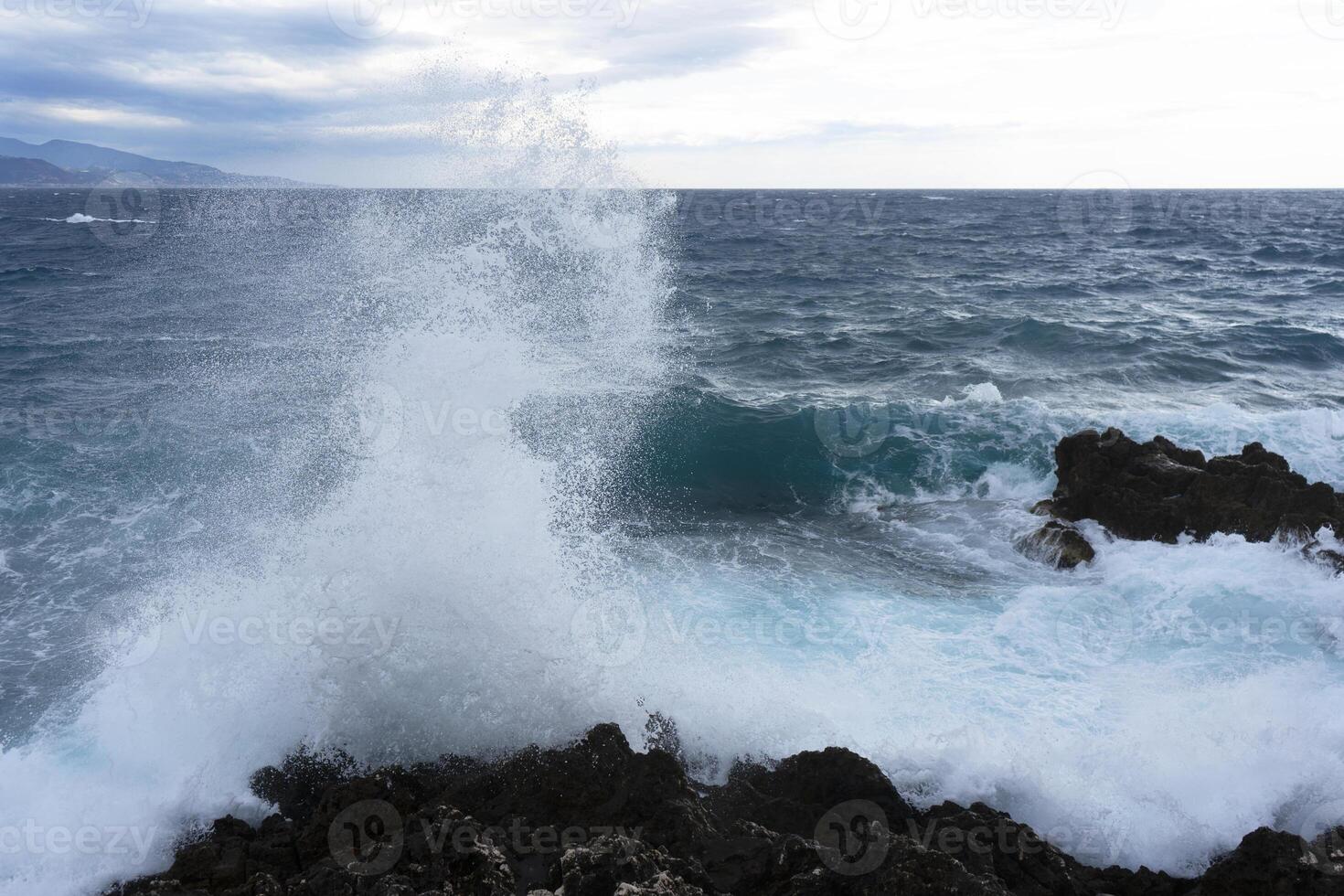 a wave crashing into the rocks photo