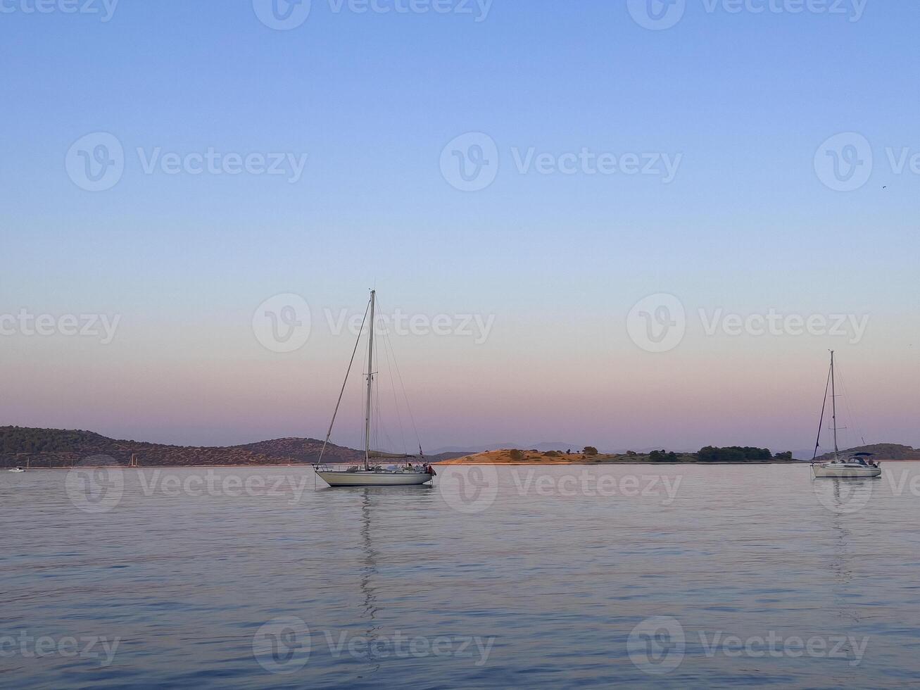 two sailboats floating in the water at dusk photo