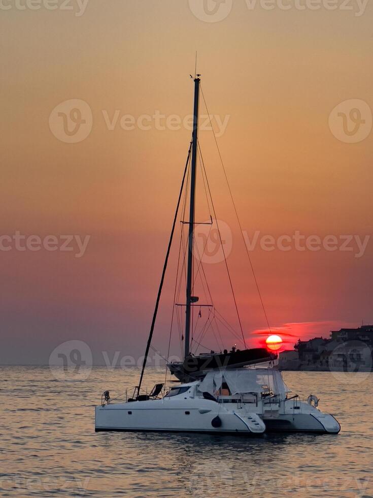 a catamaran sailing in the ocean at sunset photo