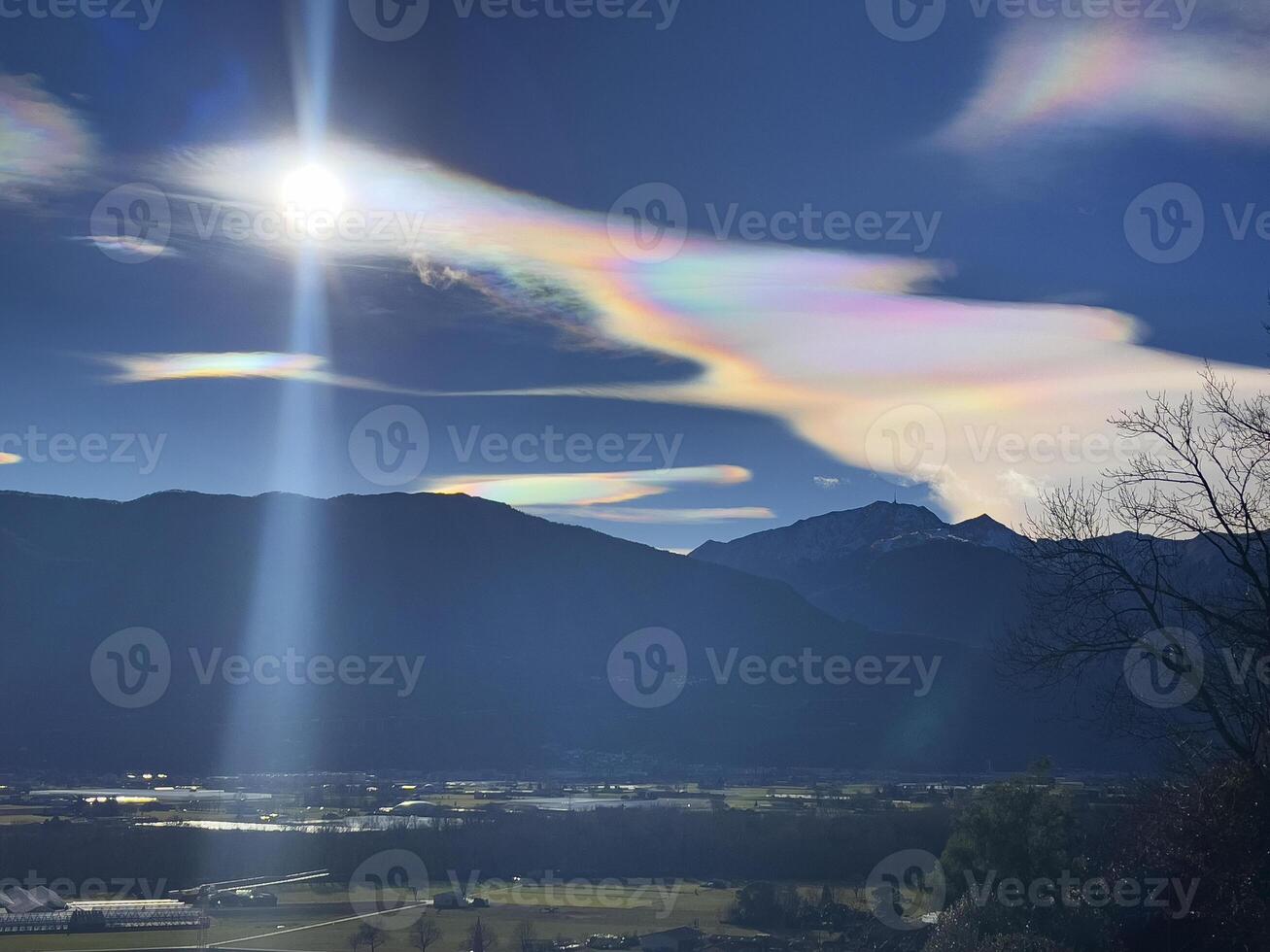 a rainbow cloud over a valley with mountains in the background photo