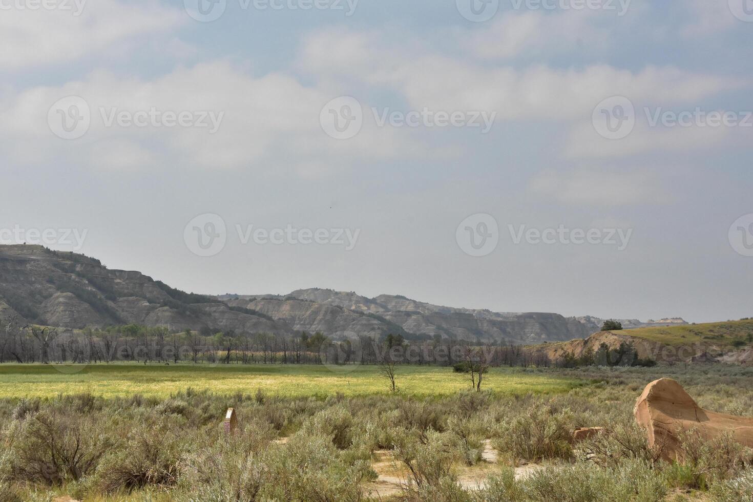Beautiful Field Surrounded by Mountains Under Thick Clouds photo