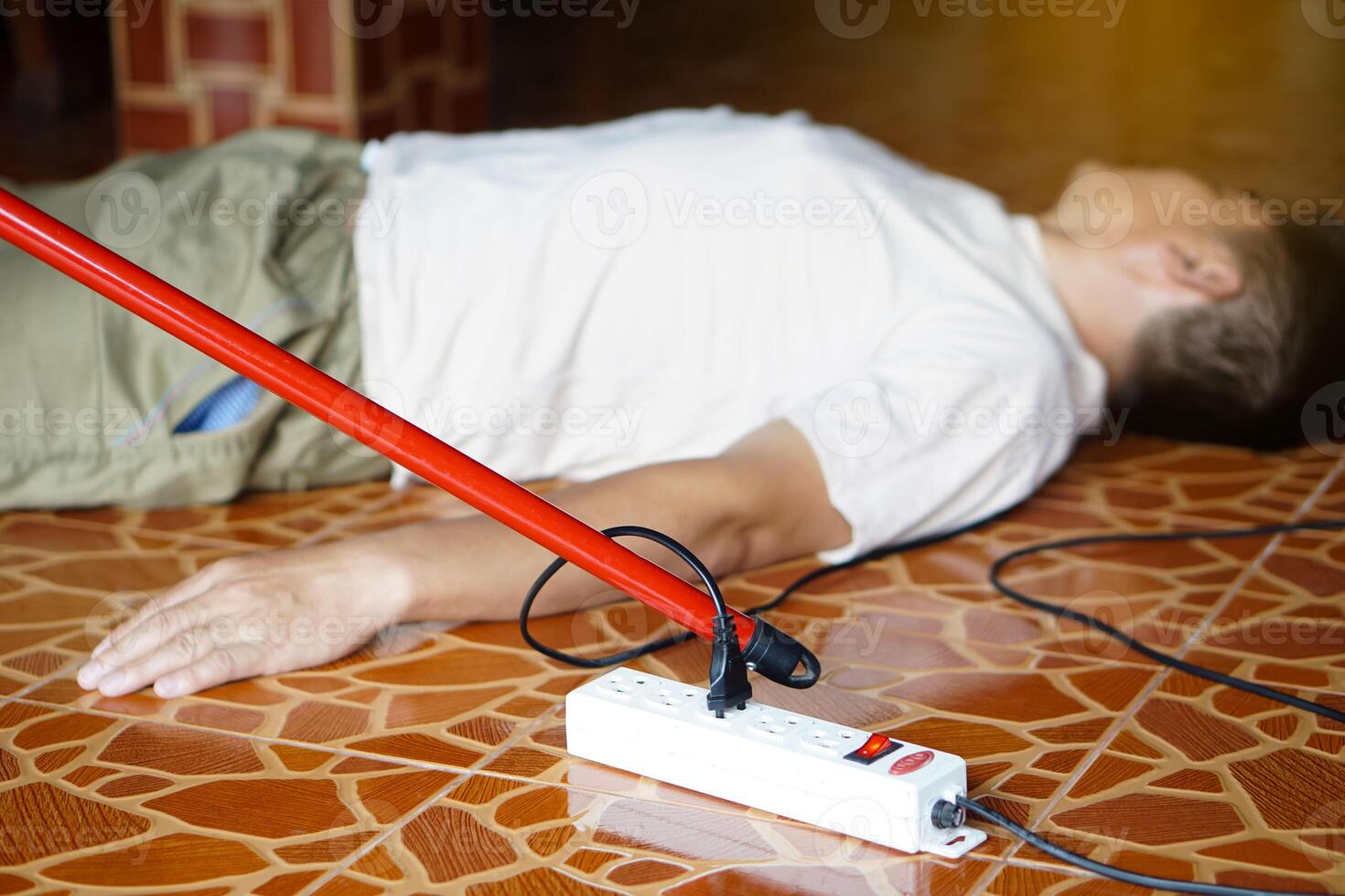 Using red plastic stick is moving away the electric plug socket from the unconscious man who lay down on the floor. Concept, Electric Shock. Emergency basic rescue. First Aid photo