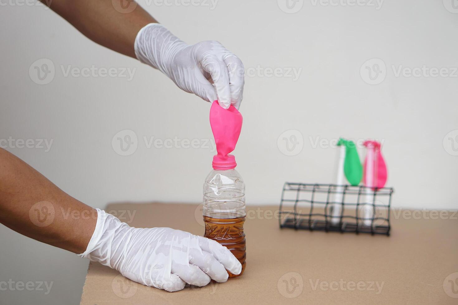 Close up hands hold  flat pink balloon on the top of pop soda bottle to do experiment about chemical reaction. Concept, science experiment about reaction of chemical substance. photo