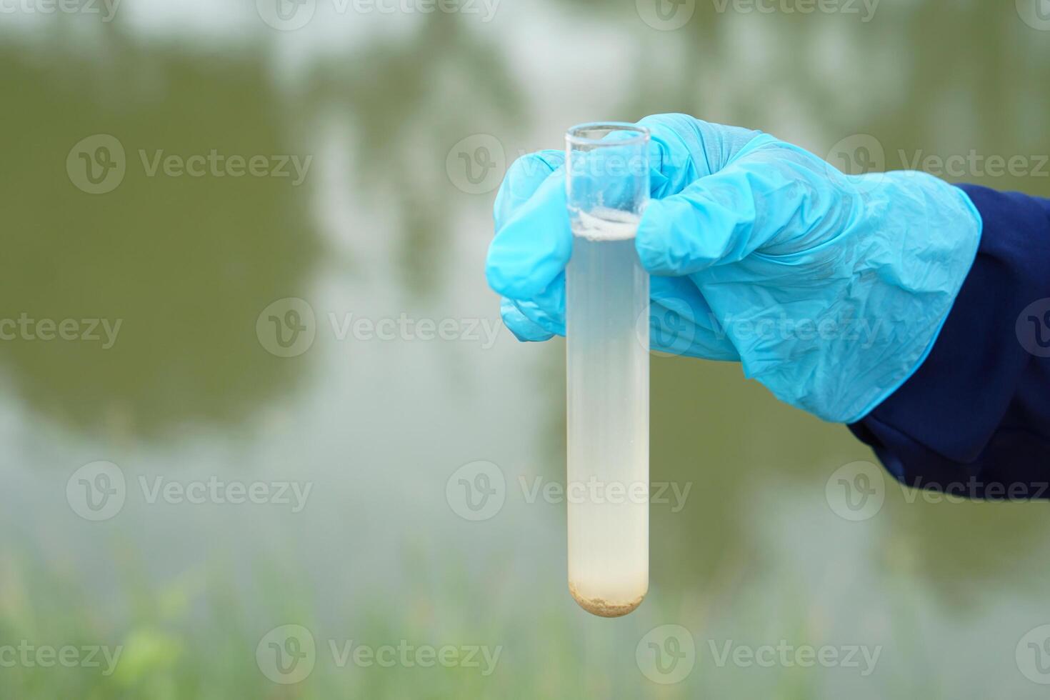 de cerca mano usa azul guante sostiene prueba tubo de muestra agua desde lago. concepto, explorar, inspeccionar calidad de agua desde natural fuente, preparar para haciendo experimento. prueba de agua contaminación. foto