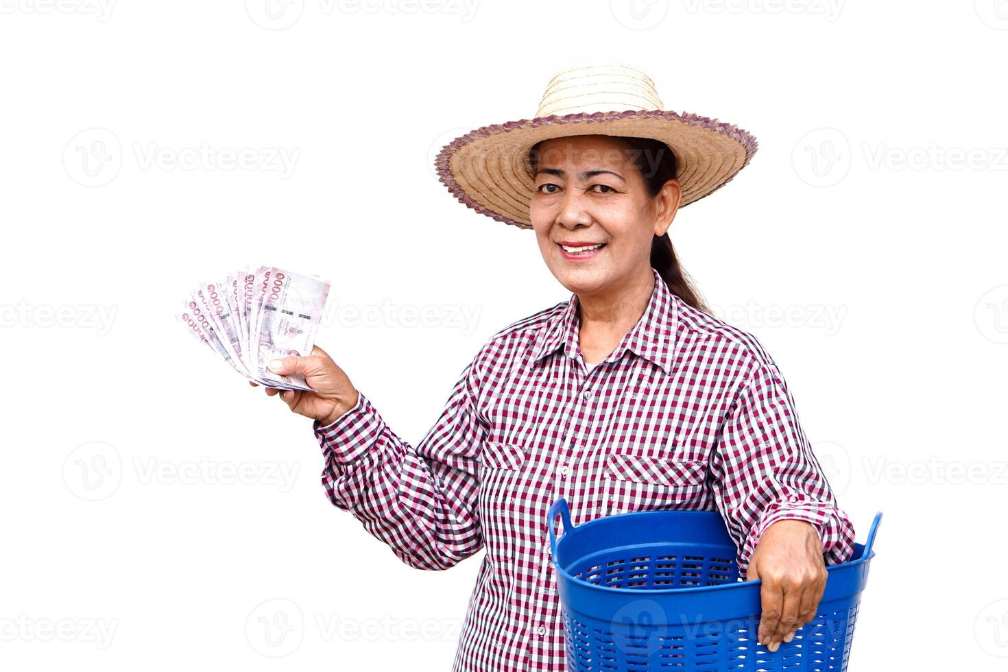 Happy Asian senior woman farmer wears hat, holds blue basket and Thai banknote money, isolated on white background. Concept, Farmer happy to get profit, income from doing agriculture. photo